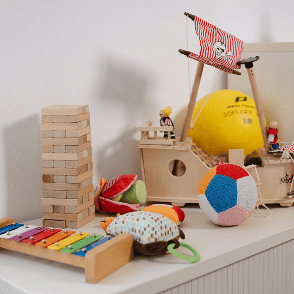 Verschiedene Spielzeuge und Spiele für Kinderbetreuung stehen auf einem Regal im Büro.